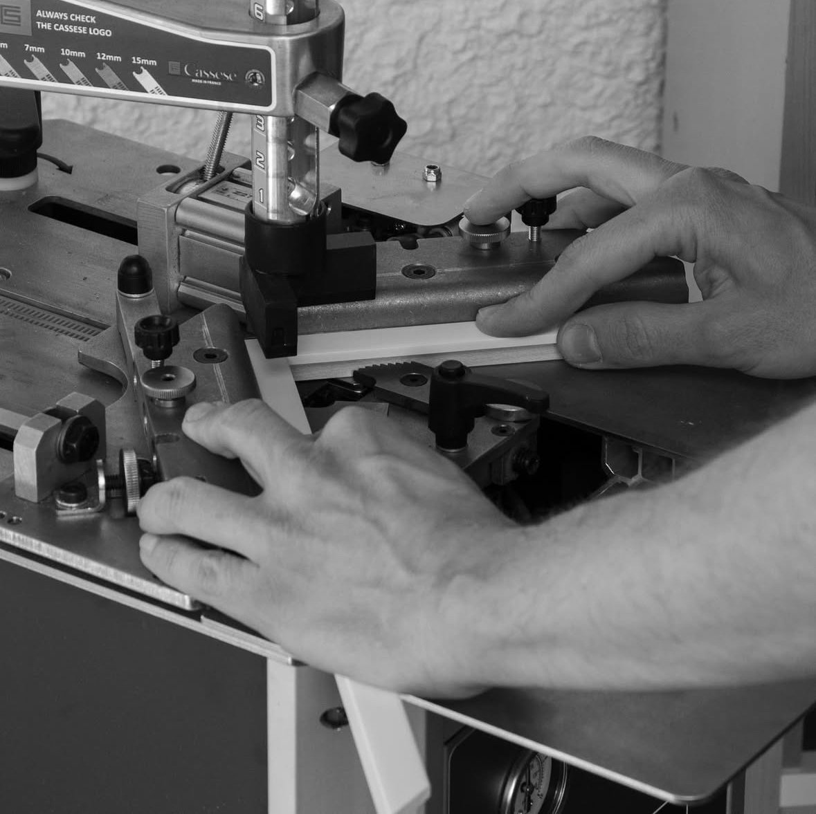 photographie des mains d'un artisan réalisant un assemblage de l'un des angles d'un cadre.